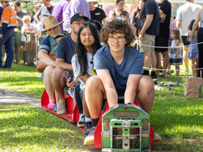 People riding a miniature train during a community event