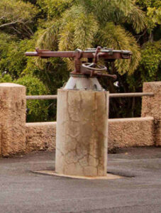 Rusted 19th‑century artillery gun displayed on a concrete base in Queen’s Park.